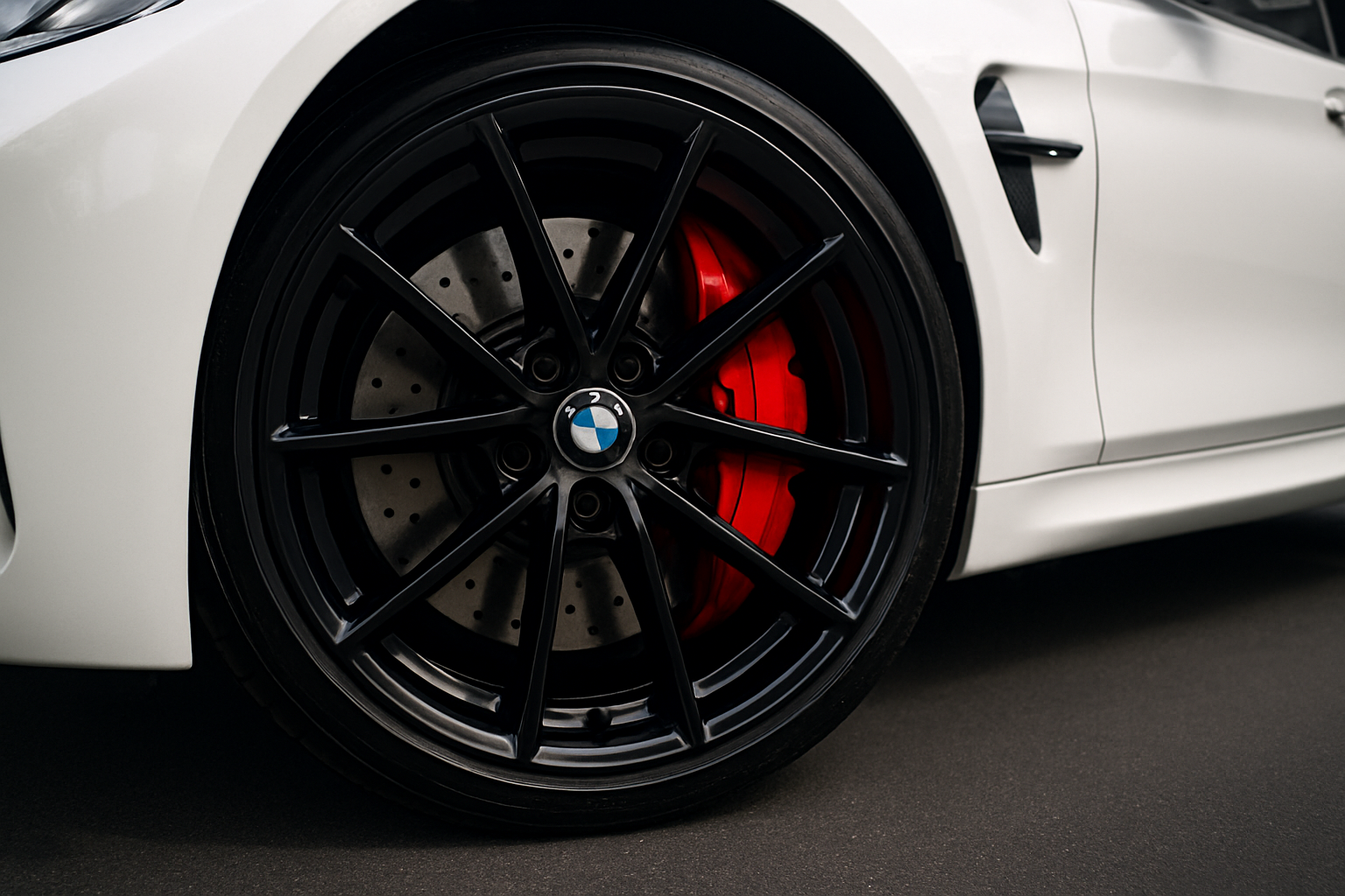 A low-angle shot of the front wheel and brake assembly on a performance car, like a BMW M3. The wheel is turned slightly to showcase the gleaming, ceramic-coated red brake caliper behind the clean, glossy spokes of the wheel. The car is parked on a dark, clean surface, making the protected wheel the undisputed hero of the image.