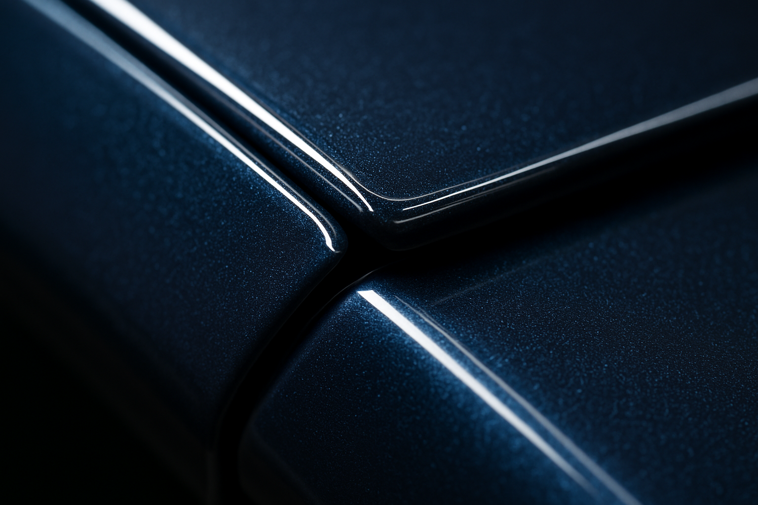 An extreme close-up, macro shot of the edge of a car's hood panel where the paint protection film has been wrapped seamlessly around the edge. The focus is razor-sharp, demonstrating how the film is virtually invisible and the installation is flawless. The car is a deep metallic blue, and the lighting highlights the paint's gloss through the clear film.